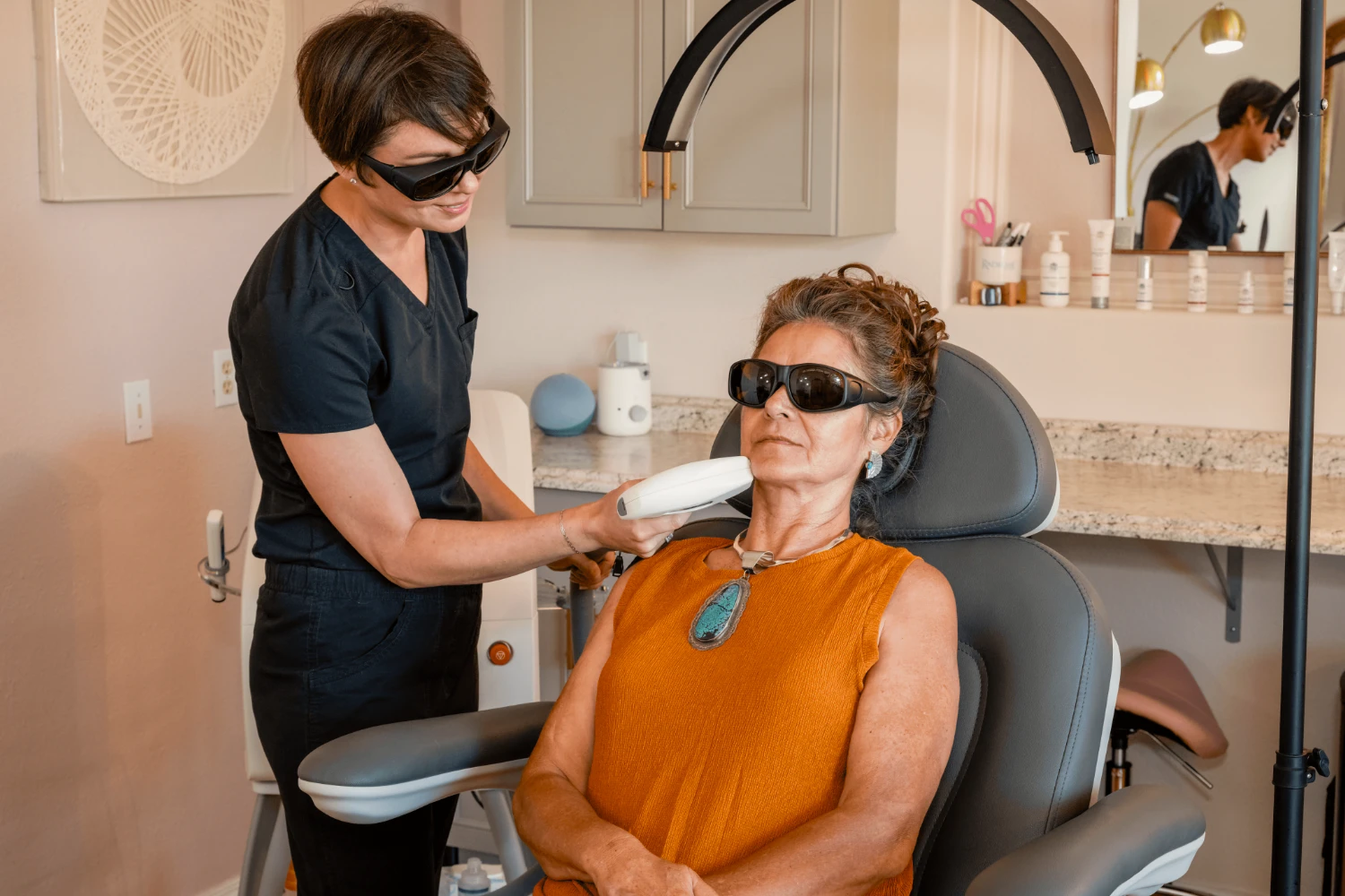 Provider applies a laser hair removal device to a patient’s face while both wear protective eyewear.